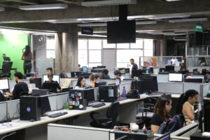 The newsroom of O Liberal newspaper in Belém, with several journalists working at their desks in a spacious and modern environment.