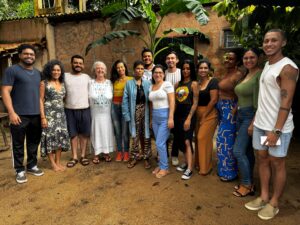 Group of journalists and communicators from Tapajós de Fato gathered outdoors, in an environment surrounded by tropical vegetation and mud walls.