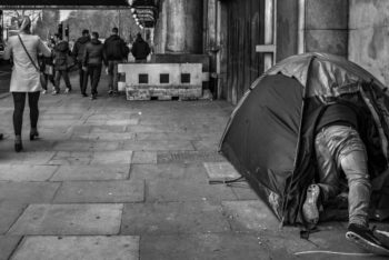 Man climbing into a tent on a dirty street