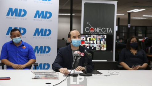 Three people wearing masks sitting behind a desk