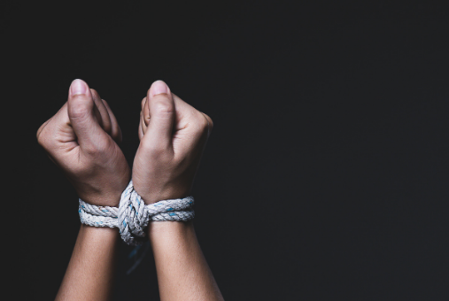 Hands tied together with rope on a black background