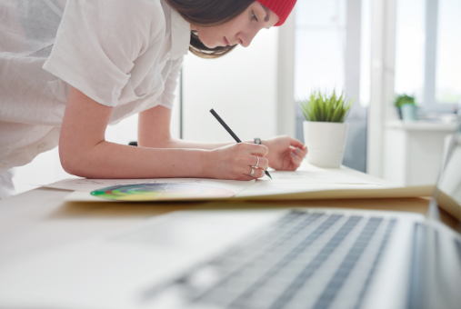 Person drawing next to a laptop