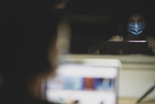 Women wearing a mask in front of computer