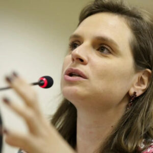 Researcher Bia Barbosa speaking at a microphone