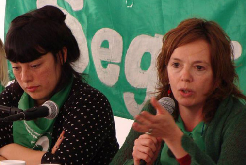 mujer hablando al micrófono con fondo verde en un festival