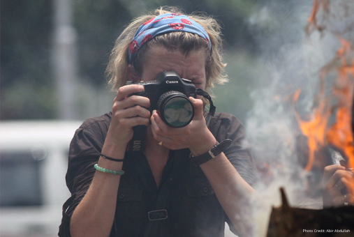 Woman journalist photographing in risky situation