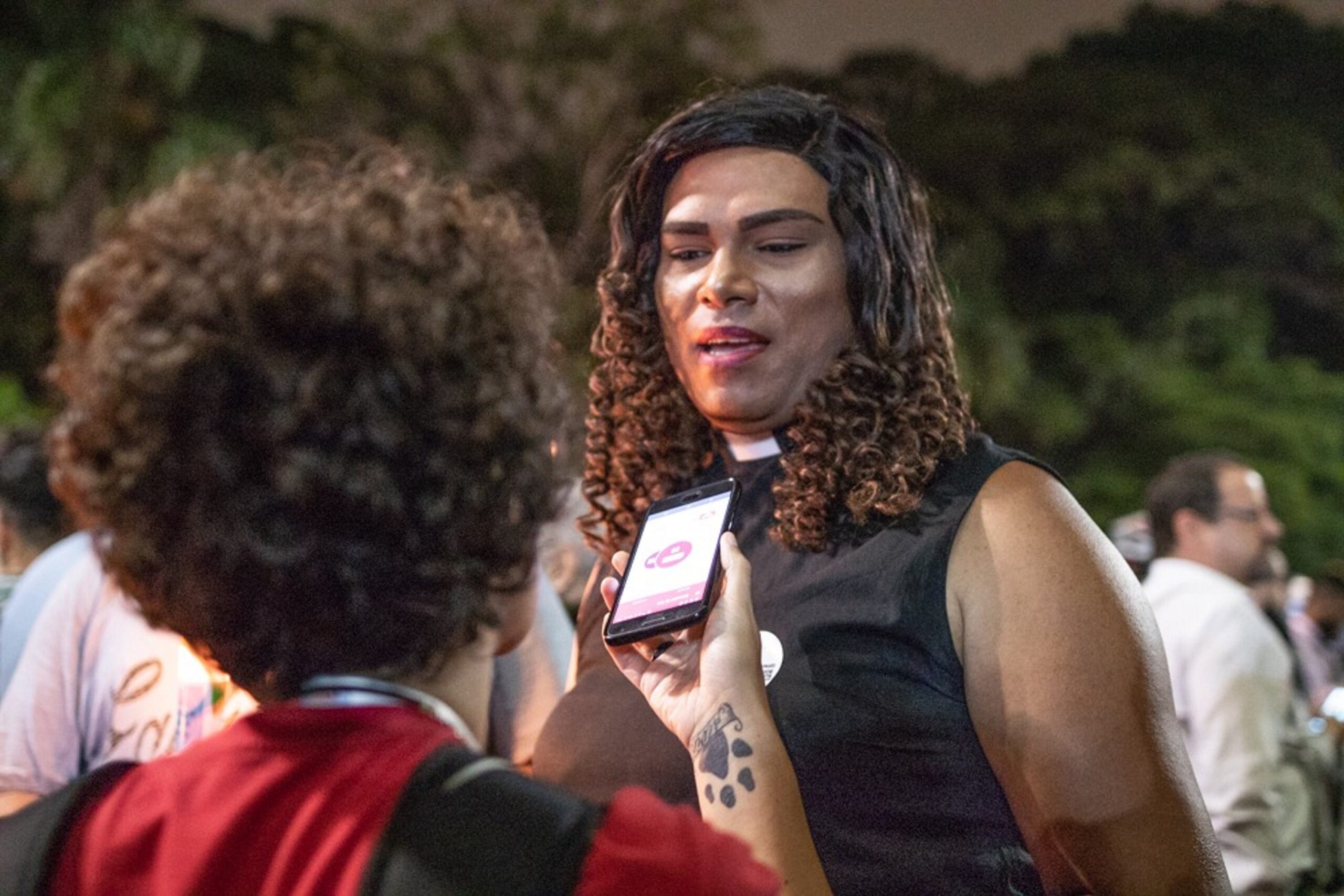 Trans woman speaks to a reporter holding a cell phone to interview her.