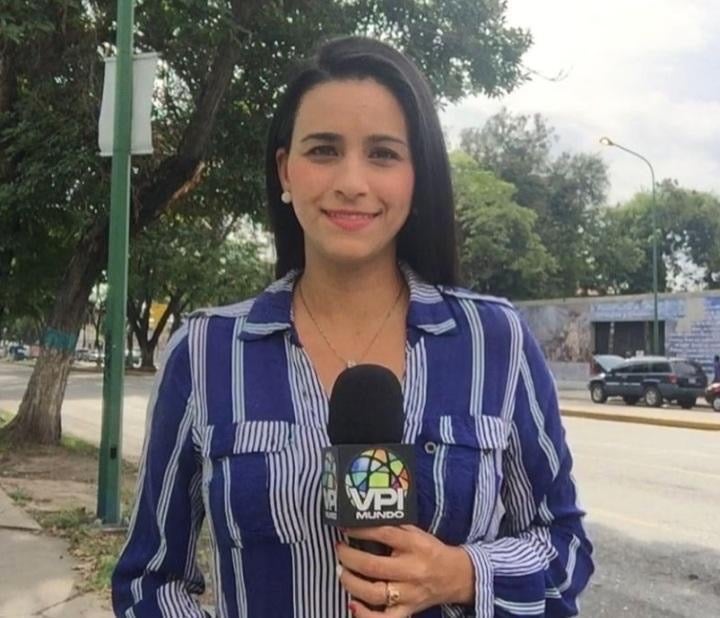 Young woman holding a microphone and smiling to the camera.