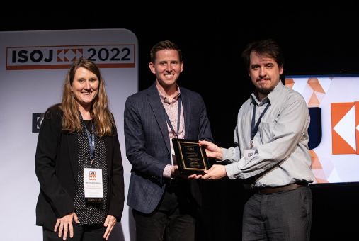 A woman and two men share ISOJ research award on stage