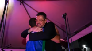Rodrigo Chaves hugging a supporter at an event, evening