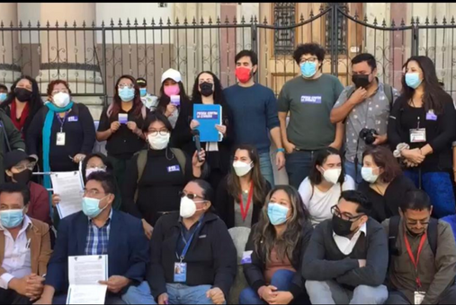 group of journalists wearing masks in front of a metal gate in Guatemala