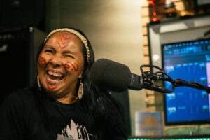 Indigenous communicator Elizângela Baré smiles in front of a microphone in a recording studio