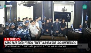 A group of men in a courthouse in Argentina waiting to hear the verdict, surrounded by guards and other people