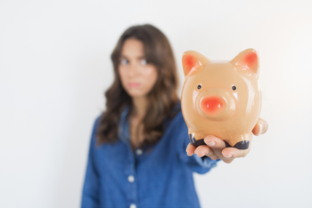 a woman with brown hair holding a piggy bank
