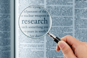 a magnifying glass on a newspaper pointing to the word "research".