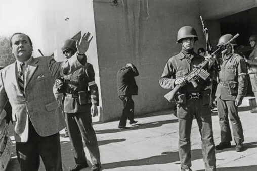 Soldiers with rifles in front of political prisoners at Chile's National Stadium in 1973