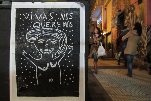 poster with a drawing and the sentence "vivas nos queremos" in a street in buenos aires