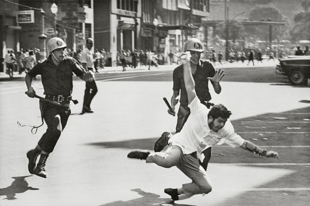 Un estudiante está a punto de caer tras la persecución de dos soldados que están a punto de golpearlo en una calle de Río de Janeiro en 1968