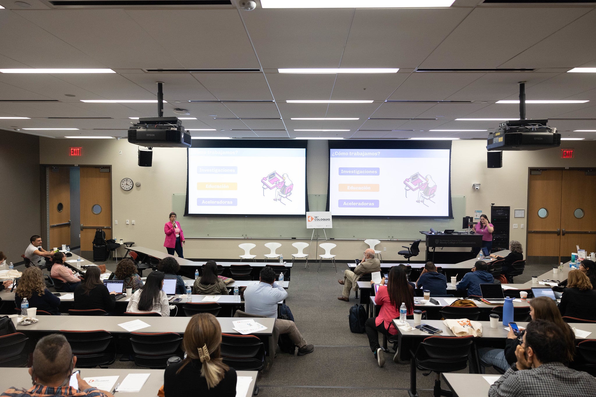 Woman standing in front of a large classroom with two screens in the background