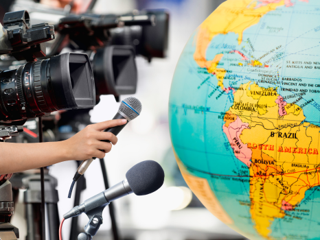 Cameras and microphones pointing at a map of Latin America on a world globe.