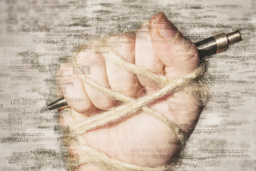 hand with pen tied to a rope, depicting the idea of freedom of the press