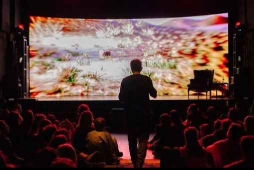 Man in front of screen showing desert