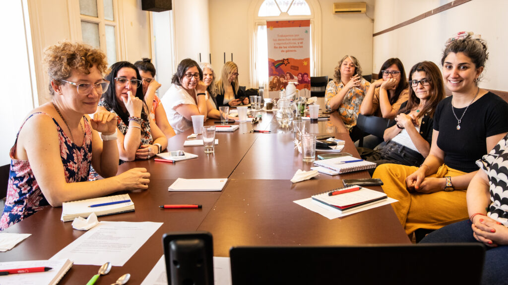 12 mujeres sentadas en una mesa durante una reunión de trabajo