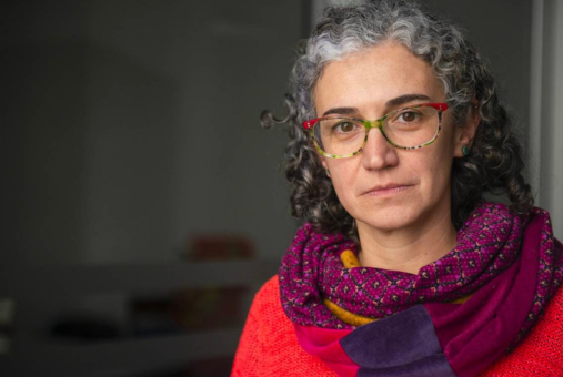 Woman with glasses and scarf looks at the camera