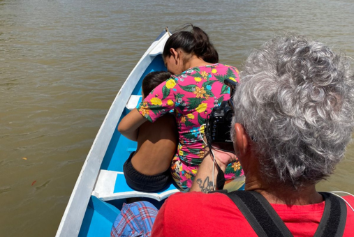 man holding camera and taking picture of woman holding a child inside a boat in a river in the Amazon