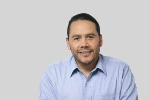 a man wearing a blue shirt and smiling to the camara