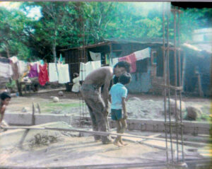 Un hombre sonriendo mirando a un niño parados en un terreno por construir