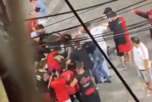  A group of people wearing red shirts surround a point on the floor, indicating the scene of Newell's fans assaulting journalism student Mauro Ayala in a football stadium