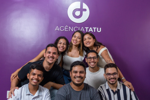 Agência Tatu team gathered in front of a purple wall