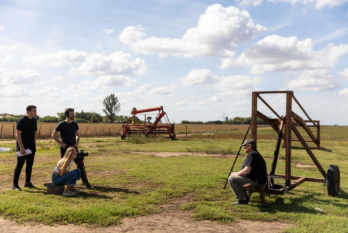 A journalism team working in a field interviewing a farmer