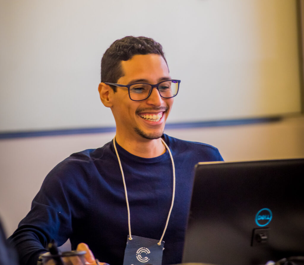 Lucas Thaynan, visualization director at Agência Tatu, smiles in front of his computer