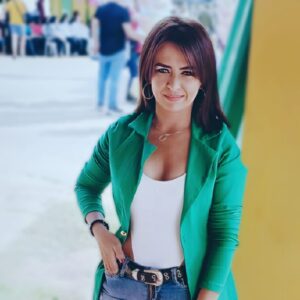 a woman journalist wearing a green blazer and posing to the camara