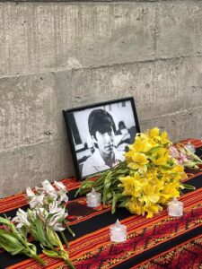 Mesa con flores y velas en homenaje a un hombre difunto cuya fotografía está sobre la mesa.