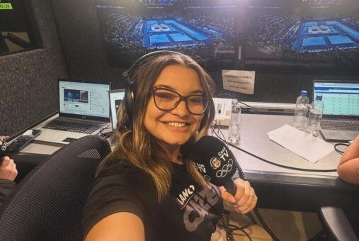 A young woman smiling, wearing glasses, inside a studio. The photo is a selfie