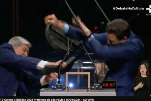 A man on the left, José Luiz Datena, throws a chair at Pablo Marçal on the right, who defends himself during a mayoral debate in São Paulo on September 15