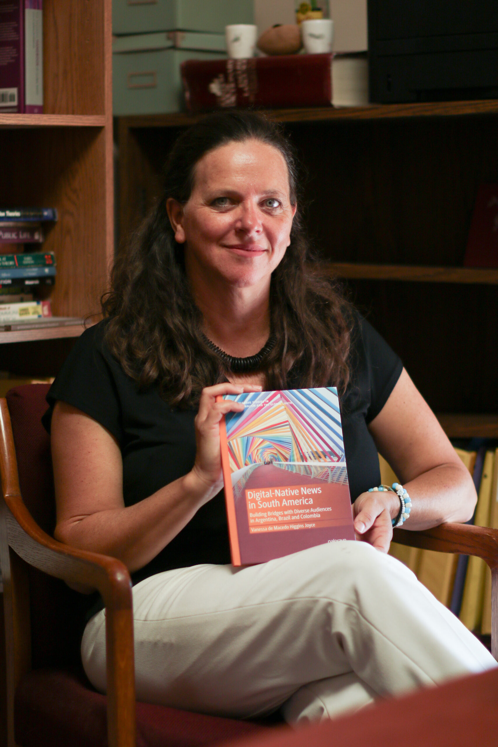 Brazilian journalist Vanessa de Macedo Higgins Joyce poses with her book “Digital-Native News in South America. Building Bridges with Diverse Audiences in Argentina, Brazil and Colombia.”