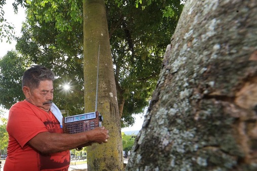 Image of a man listening to the radio among trees in the Brazilian state of Acre