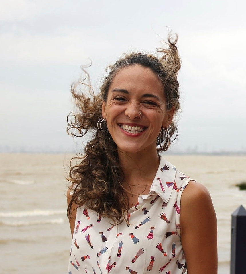 woman standing by a river smiling at the camera