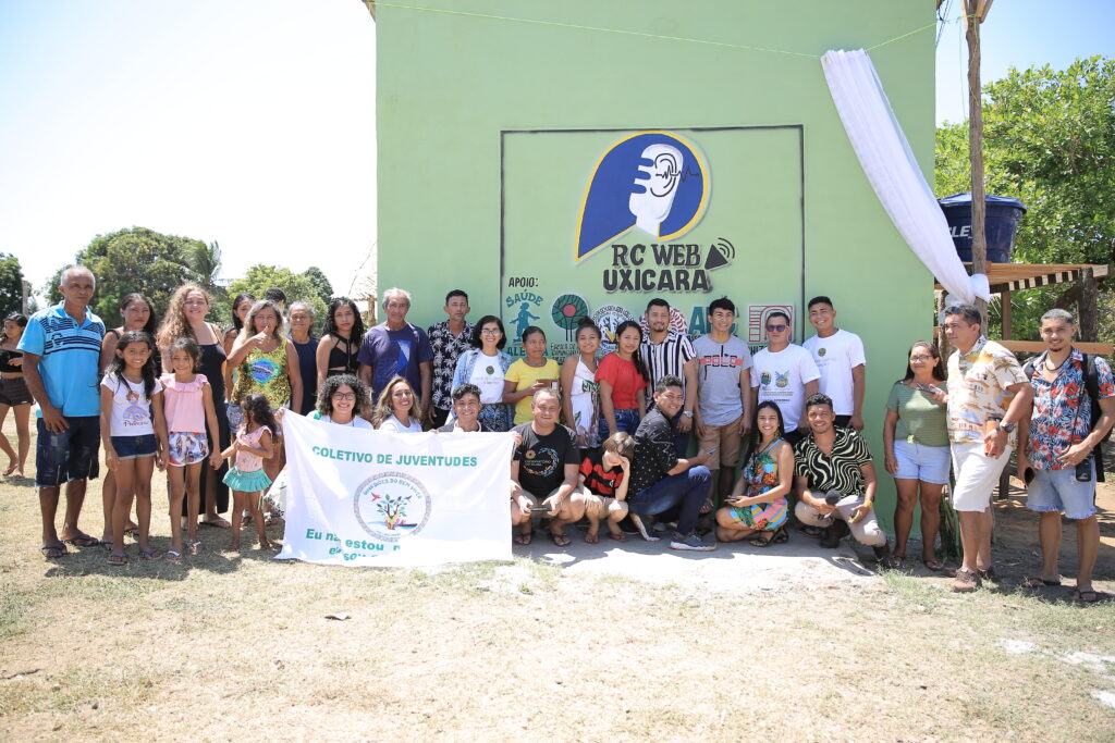 People gathered in front of a building with the name of the Uxicará web radio, in Santarém, Pará, Brazil