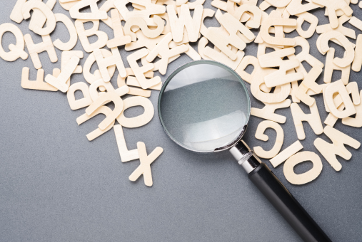 Magnifying glass on the pile of wooden English alphabets