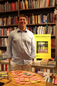 Man smiling in front of cover of book