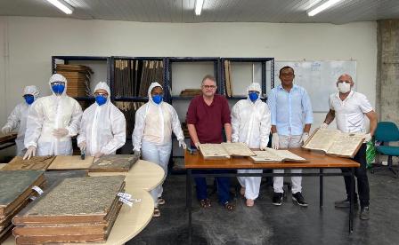 Eight people working in special suits to preserve newspapers