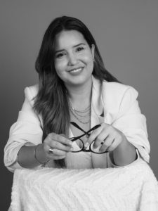 a woman holding her glasses and smiling to the camera