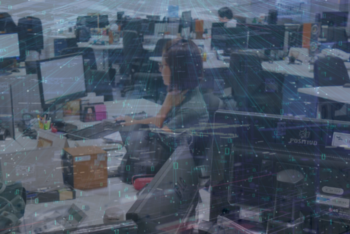 A newsroom filled with desks, computers, and journalists working at their stations, overlaid with a digital matrix of binary code and data lines, symbolizing the integration of artificial intelligence in journalism.