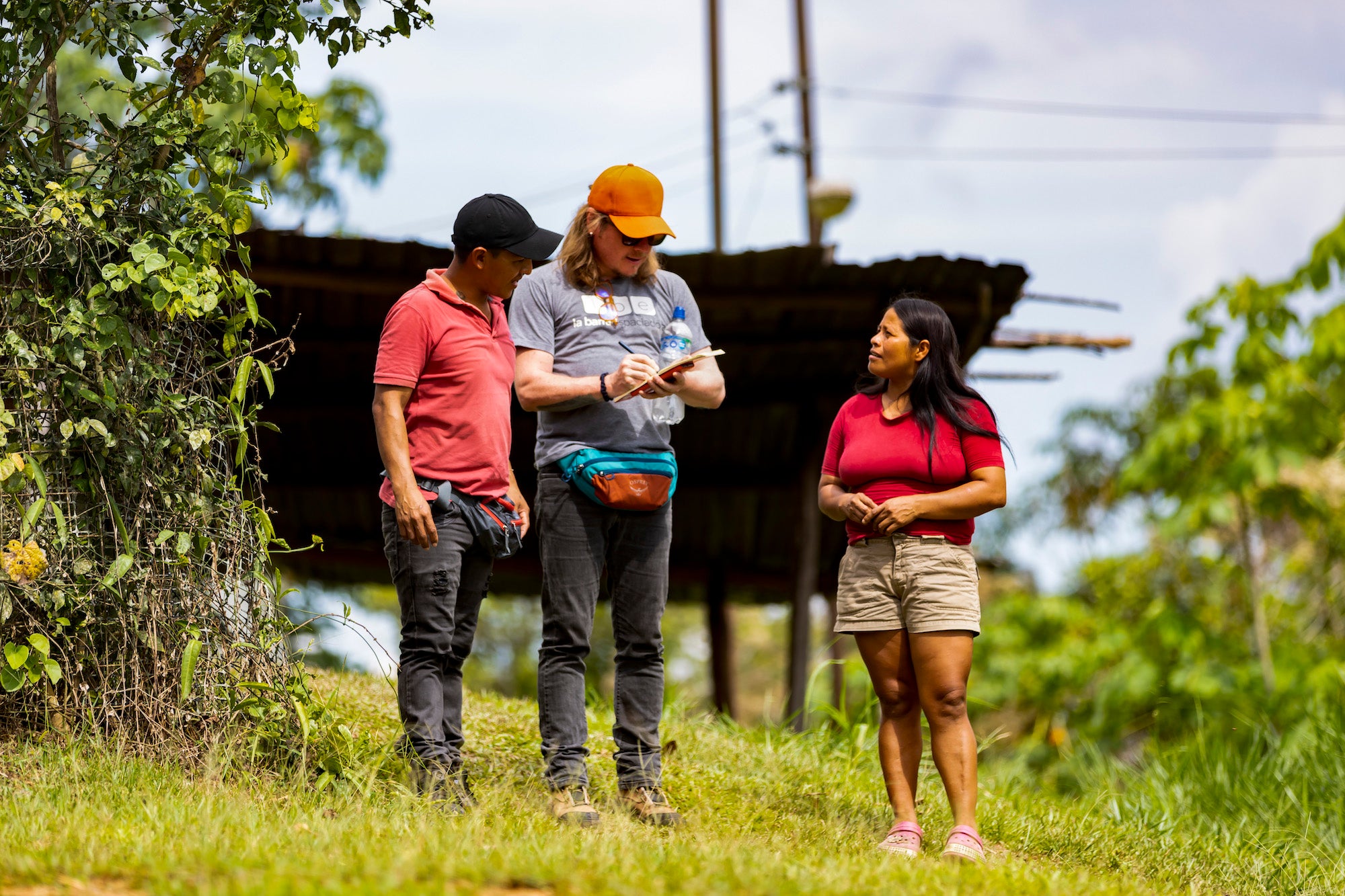 A group of people talking outdoors in a rural setting, with one person taking notes. (Foto: Cortesía Mongabay Latam)