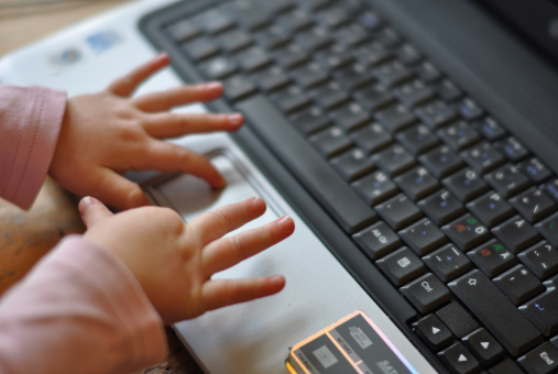 Close-up of a child's small hands typing on a laptop keyboard, symbolizing digital engagement from an early age